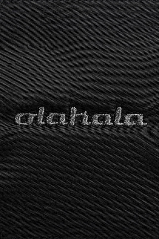 Nahaufnahme eines schwarzen, robusten Nylon-Gewebes der Sports Bag mit Ziernähten und gesticktem OLAKALA Logo; verstellbarer Schulterriemen und Reißverschluss-Innentasche.