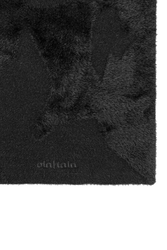 Nahaufnahme eines weichen, schwarzen Schals mit unregelmäßigem Muster und OLAKALA-Logostickerei, Modell Greyzone Fuzzy Scarf Black, Länge 180 cm, Breite 35 cm.