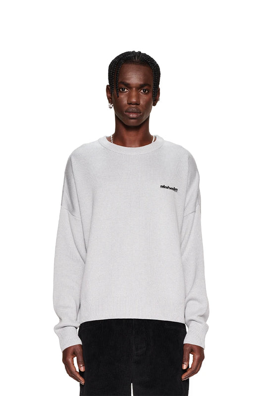 Mann mit Zöpfen trägt den CC Knit Sweater Gray mit überschnittenen Schultern und OLAKALA Metallpin, präsentiert in oversized Unisex-Passform.