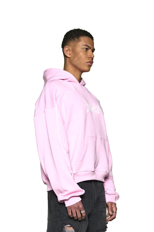 Ein Mann im Defect ID Hoodie Pink mit Feinstrickbündchen an Ärmeln und Saum, zeigt Siebdruckgrafik auf der Brust. Oversized und cropped Fit.