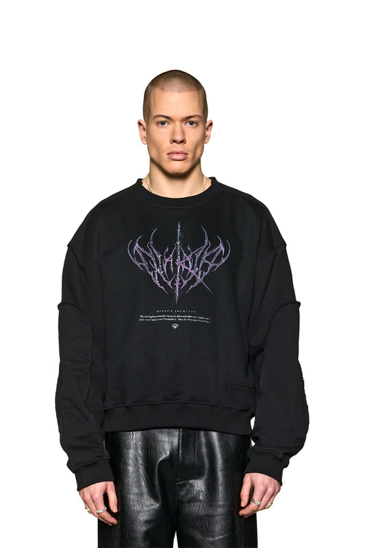 Man wears Defect ID Sweater Black with Defect Identity graphic on the chest and ribbed cuffs and hem. Oversized fit.