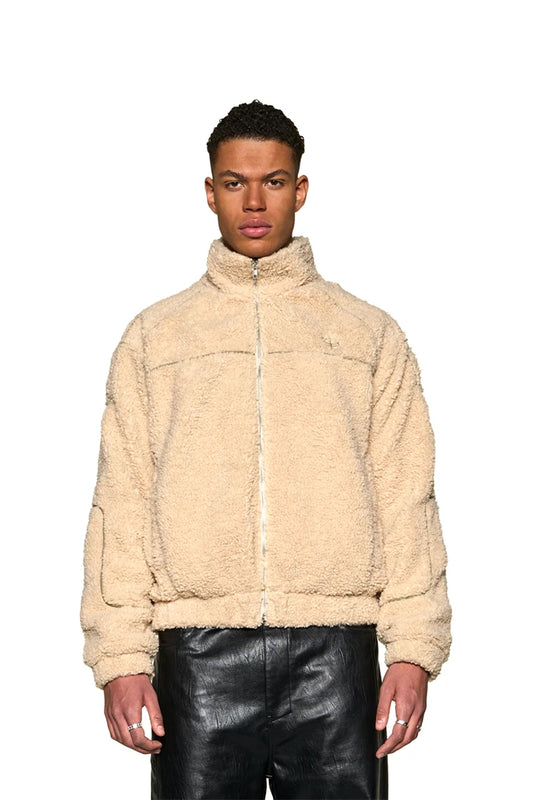 Mann trägt Distorted Teddy Jacket mit gesticktem OLAKALA Logo und Defect Identity-Icon, elastischen Bündchen und Eingriffstaschen, Oversized-Passform.