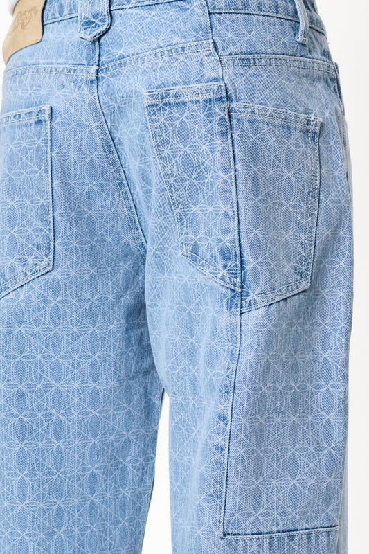 Nahaufnahme der CC Blue Monogram Denim Pants mit versetztem Hosenbund und Mittelfinger-Patch, zeigt die detaillierte Verarbeitung und das OLAKALA-Monogramm.