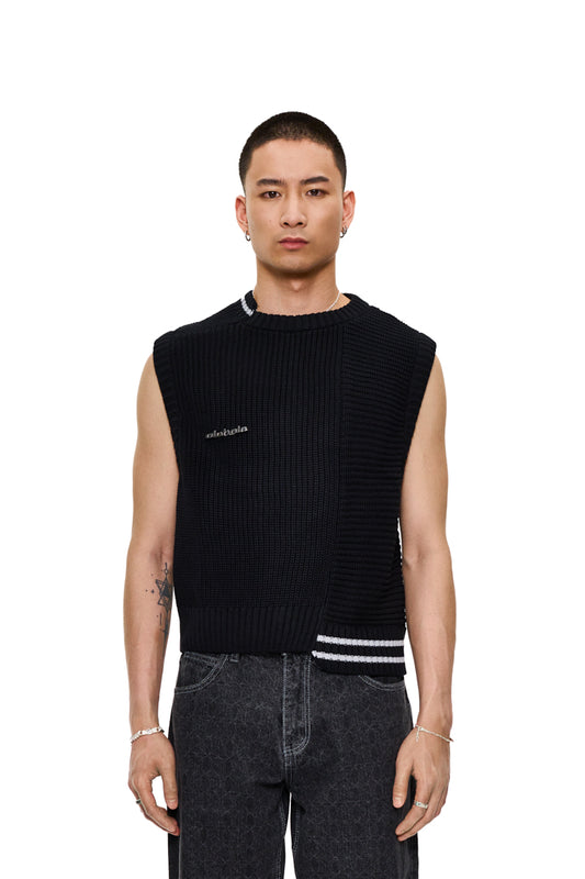 Mann trägt CC Knit Vest Black mit verschiedenen Strickmustern, versetztem Kragen und abnehmbarem OLAKALA Metall-Pin. Oversized, cropped, unisex Design.