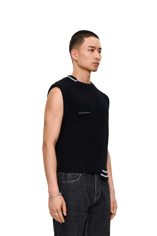 Mann trägt den CC Knit Vest Black mit verschiedenen Strickmustern und abnehmbarem OLAKALA Metall-Pin, oversized und cropped Unisex-Design.
