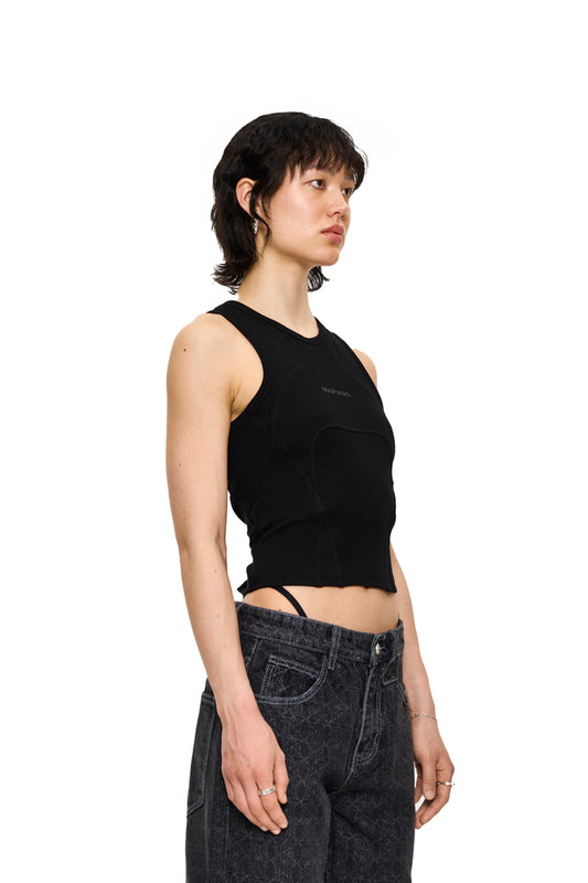 Frau trägt eng anliegendes, besticktes OLAKALA CC Anatomy Tanktop Cropped Schwarz mit Ziernähten, betont Taille und Oberkörper.