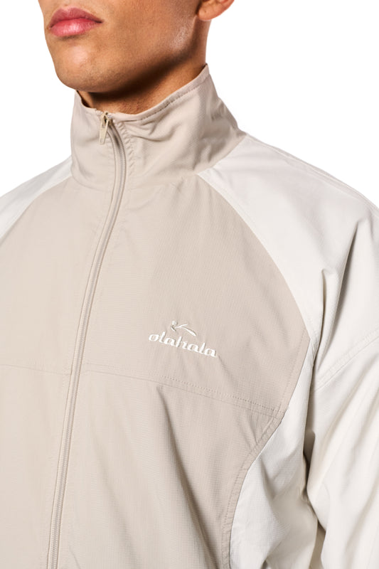 Nahaufnahme einer Herrenjacke mit Teilungsnähten, elastischen Bündchen und gesticktem OLAKALA Sports Logo. Reißverschlusstaschen und robuster Rip-Stop Stoff sind sichtbar.