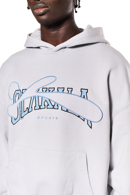 Person trägt graues Sports Hoodie mit blauer OLAKALA Sports Grafik, Oversized Passform, Ripp-Bündchen und Teilungsnähten an Ärmeln. Unisex-Design.