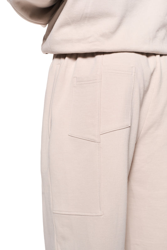 Nahaufnahme einer Tasche der Sports Sweatpants Beige mit Reißverschluss, elastischem Bund und gesticktem OLAKALA Sports Icon.