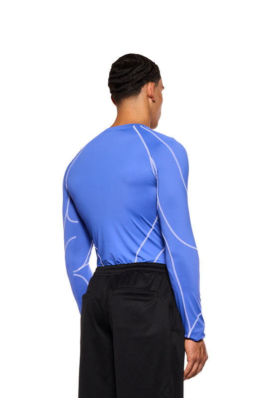 A man wears the close-fitting Sports Anatomy Tech Top Blue with decorative stitching and OLAKALA Sports logo on the left chest.