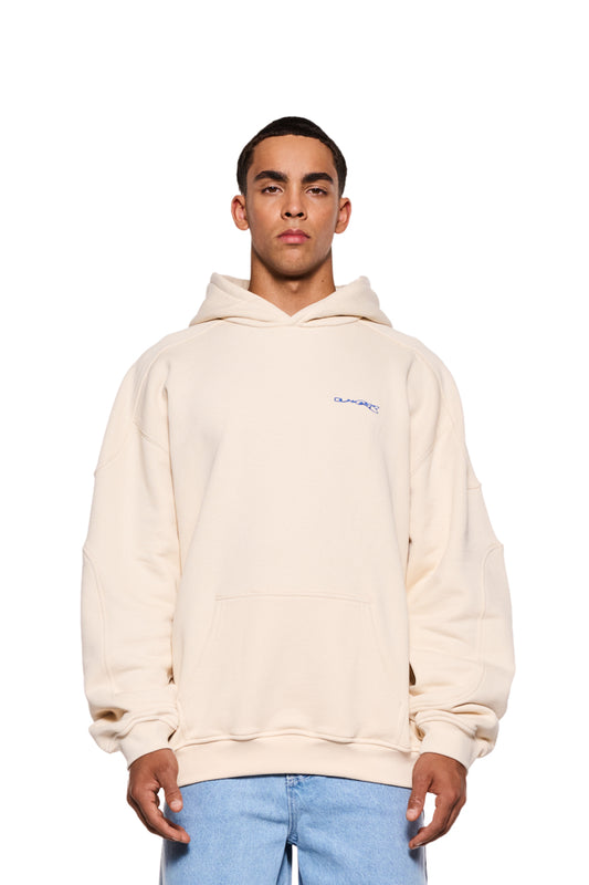 Mann trägt Synergy Mask Hoodie Beige mit Rippbündchen, elastischem Bund und abnehmbarer Maske; blaue Synergy-Stickerei auf Brust, Grafikdruck auf Rücken.