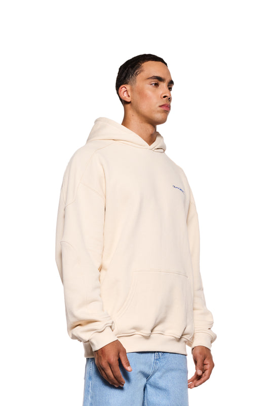 Ein Mann im weißen Synergy Mask Hoodie Beige mit abnehmbarer Maske, blauer Stickerei auf der Brust und Synergy-Grafik auf dem Rücken. Unisex, oversized Fit.
