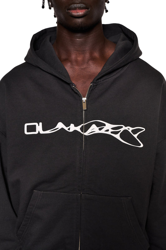 Person wearing Synergy Zip Hoodie Black with white Synergy logo, 2-way zipper and dividing seams on the sleeves, oversized fit, unisex design.