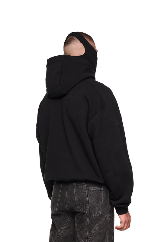 Mann trägt Alien Intel Mask Hoodie mit Siebdruck-Grafik vorne, Rippbündchen, elastischem Saum, Teilungsnähten und Kapuze; oversized und unisex.