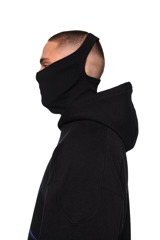 Mann trägt Alien Intel Mask Hoodie mit Siebdruck, Rippbündchen an Ärmeln, elastischem Saum und Teilungsnähten an Schultern und Kapuze. Unisex, oversized und cropped.