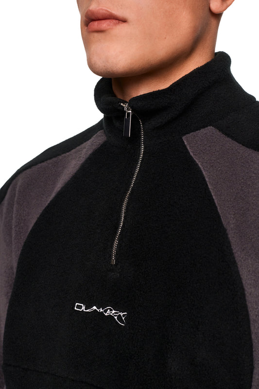 Alien Intel Fleece Halfzip Black mit hohem Kragen, Brustreißverschluss, gesticktem „Synergy“-Logo und elastischen Bündchen, zeigt den Oberkörper eines Mannes im Detail.