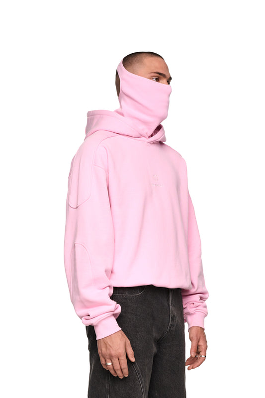 Mann trägt Discreet Mask Hoodie Pink mit gesticktem OLAKALA-Icon, Ripp-Bündchen und Kapuze. Oversized, cropped Unisex-Passform.