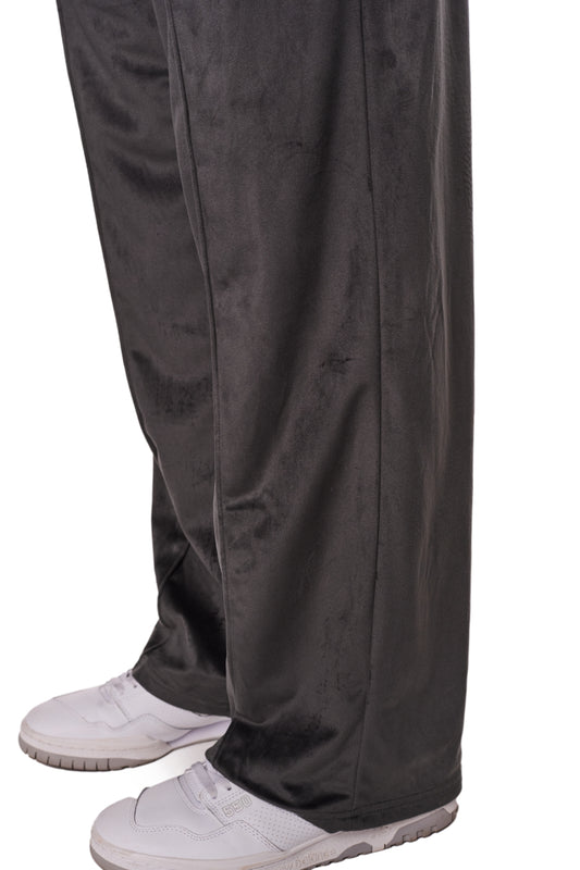 Eine Person trägt die Sports Velour Jogger Pants mit offenem Beinabschluss und gesticktem OLAKALA-Icon, kombiniert mit weißen Schuhen.
