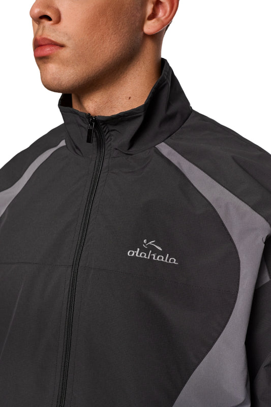 Nahaufnahme einer Sportjacke aus robustem Rip-Stop-Gewebe mit gesticktem OLAKALA Sports Logo auf der linken Brust und elastischen Bündchen für optimale Passform.