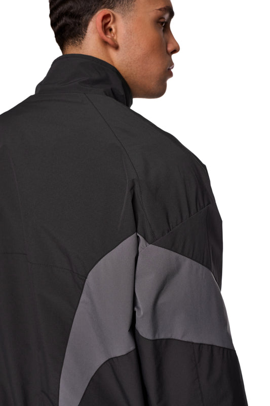 Mann trägt schwarze und graue Sports Trackjacket mit gesticktem OLAKALA Sports Logo auf der Brust, elastischen Bündchen und sportlichem Design.