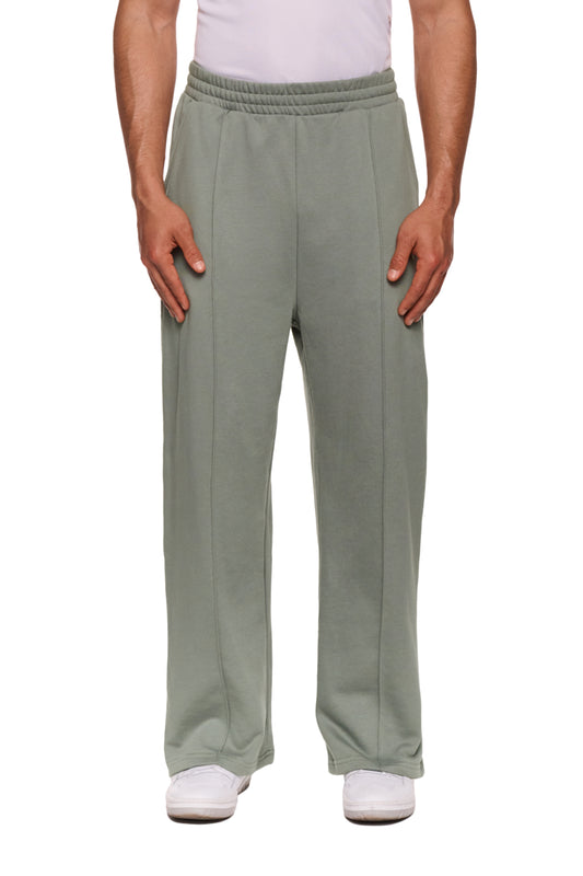 Person trägt graue Sports Loose Fit Sweatpants mit elastischem Bund und gesticktem OLAKALA Logo. Lockerer Sitz, offene Beinabschlüsse, unisex Design.