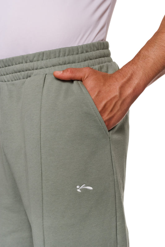Person trägt graue Sports Loose Fit Sweatpants mit elastischem Bund und OLAKALA Sports Logo, Hand in Tasche, lockere Passform für Komfort.