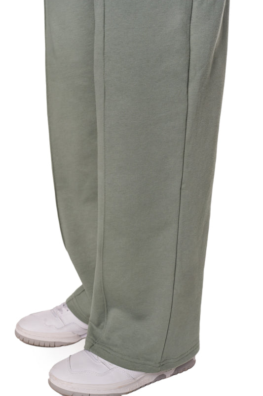 Person trägt graue Sports Loose Fit Sweatpants mit elastischem Bund und gesticktem OLAKALA Sports Logo am linken Bein, kombiniert mit weißen Schuhen.
