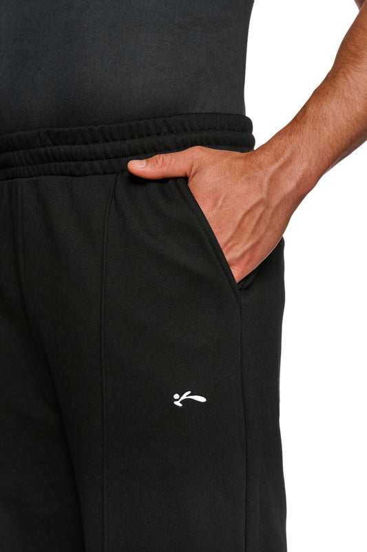 Person trägt OLAKALA Sports Loose Fit Sweatpants Black mit gesticktem Logo auf dem linken Bein, elastischem Bund und lockerer Passform.
