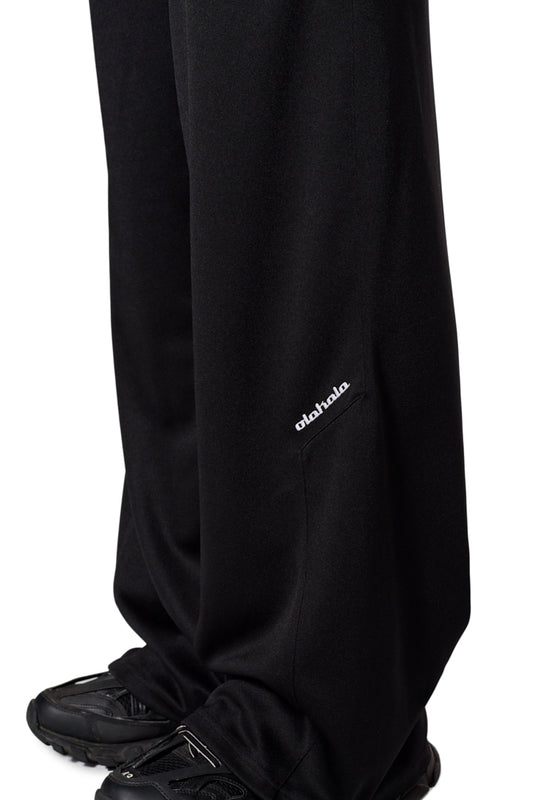 Person trägt CC Jogger Pants Black mit elastischem Bund und Logo-Stickerei, kombiniert mit schwarzen Schuhen. Ideal für lässigen Stil, erhältlich im OLAKALA Onlineshop.