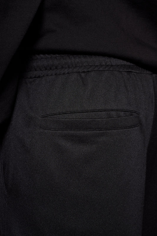 Nahaufnahme einer Tasche der CC Jogger Pants Black mit französischen Eingriffstaschen und elastischem Bund, das gestickte OLAKALA Logo sichtbar.
