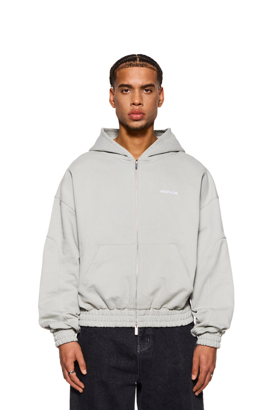 Mann trägt CC Zip Hoodie Pussywillow Gray mit gesticktem OLAKALA Logo, sichtbarem 2-Wege-Reißverschluss und elastischen Bündchen, präsentiert in lässiger, oversized Passform.