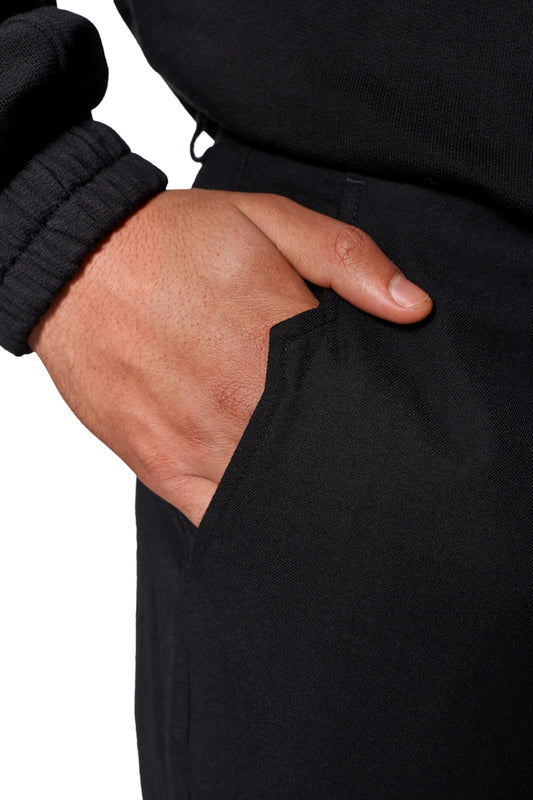 Nahaufnahme einer Hand in der Tasche einer Gills Dress Pants, die französische Taschen und ein gesticktes OLAKALA Logo über der rechten Gesäßtasche zeigt.