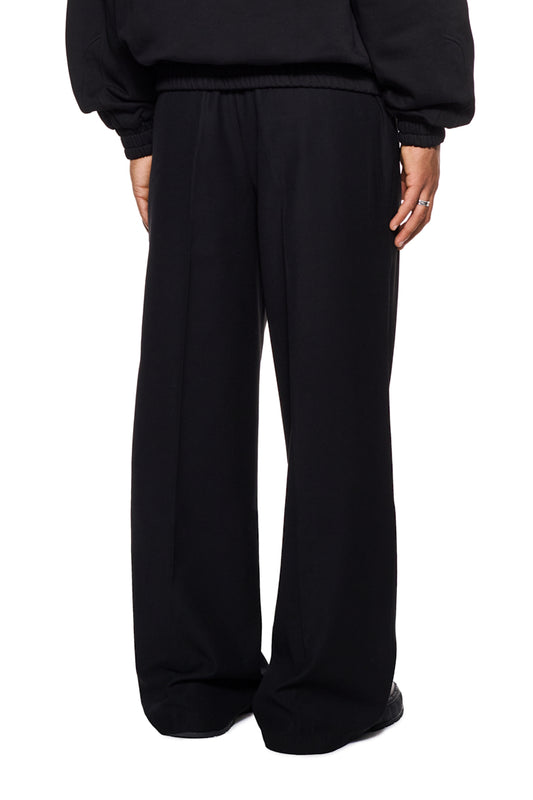 Gills Dress Pants mit asymmetrischem Tascheneingriff und OLAKALA Logo über der Gesäßtasche, lockere Passform aus robustem Köper-Gewebe, getragen von einer Person.