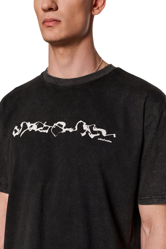 Mann trägt E.O.I. T-Shirt Black mit Ripp-Kragen und Siebdruck-Grafik auf der Vorderseite, in regulärer Passform und Washed-Optik, unisex.