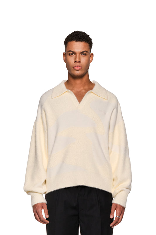 Mann trägt weißen Glitched Fuzzy Polo Cream mit Polo-Kragen, knopfloser Leiste und gesticktem Synergy-Logo auf der Brust; flauschiges Material, unisex.