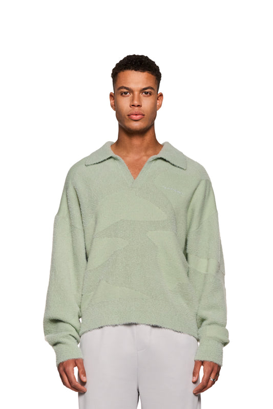 A man wears the Glitched Fuzzy Polo Mint with polo collar, ribbed cuffs and embroidered Synergy logo on the chest.