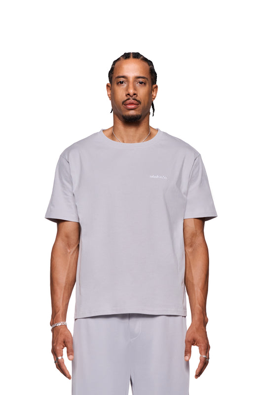 Mann trägt CC T-Shirt Regular Gray mit gesticktem OLAKALA Logo auf der Brust, reguläre Passform, unisex.