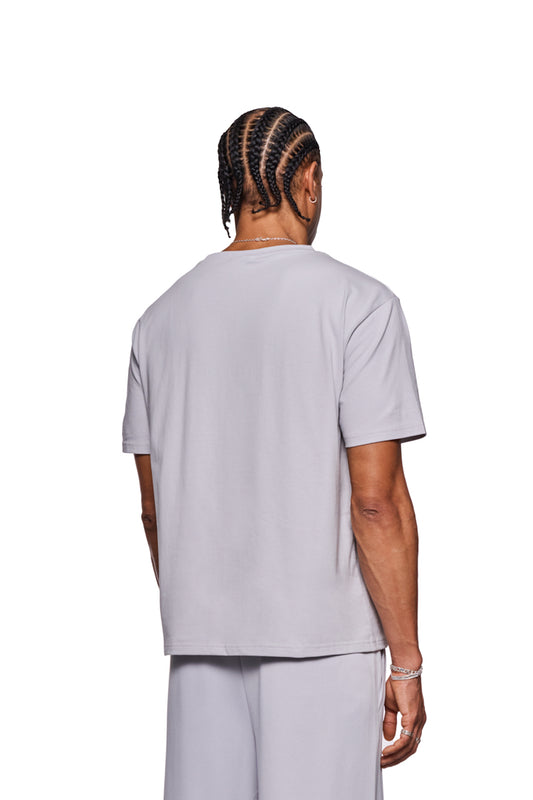 Mann in weißem CC T-Shirt Regular, zeigt Ripp-Kragen und gesticktes OLAKALA Logo auf der Brust, unisex mit regulärer Passform.