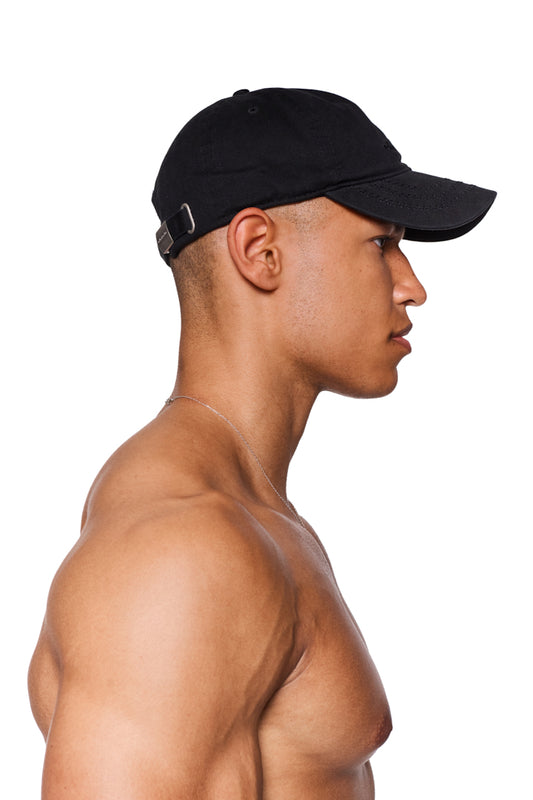 Mann mit der CC Cap All Black, verstellbar mit Metallclip, gesticktes OLAKALA Logo vorne, präsentiert im Profil.