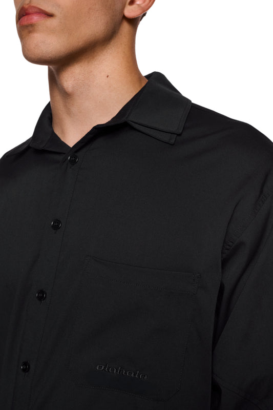 Close-up of the CC Anatomy Shirt Black with double-layer collar, button placket and embroidered OLAKALA logo on the breast pocket. Unisex, loose fit.