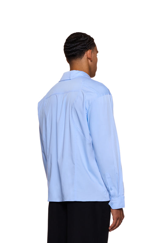 Mann trägt CC Anatomy Shirt Blue mit Knopfleiste, doppeltem Kragen, Brusttasche mit OLAKALA Logo und lockerer Passform.