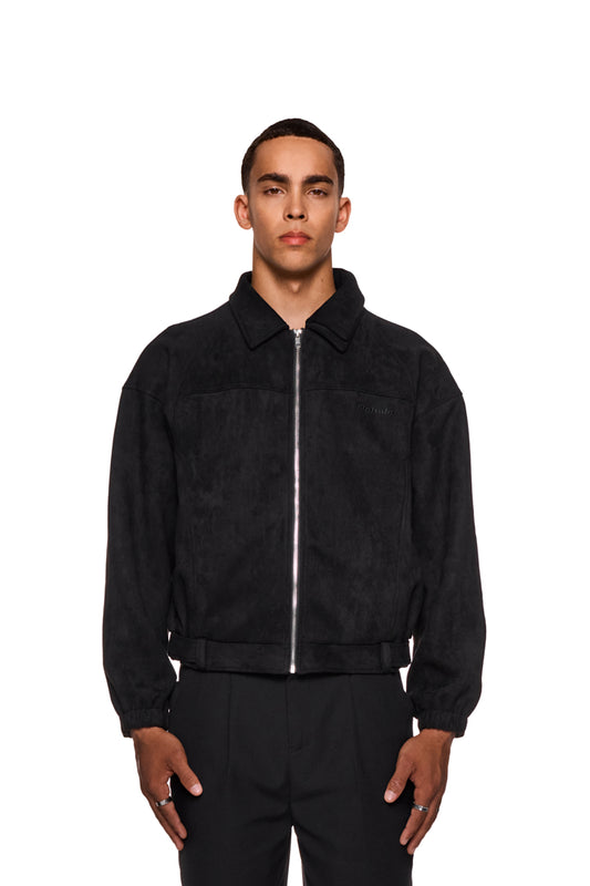 Mann trägt CC Anatomy Velour Jacket Black mit doppellagigem Kragen, asymmetrischem Rücken und gesticktem OLAKALA Logo. Hände in Paspeltaschen, elastische Ärmelbündchen sichtbar.