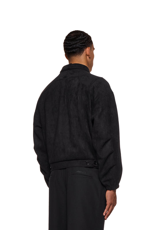 Mann trägt CC Anatomy Velour Jacket Black mit doppeltem Kragen, asymmetrischem Rücken, Paspeltaschen und gesticktem OLAKALA Logo.