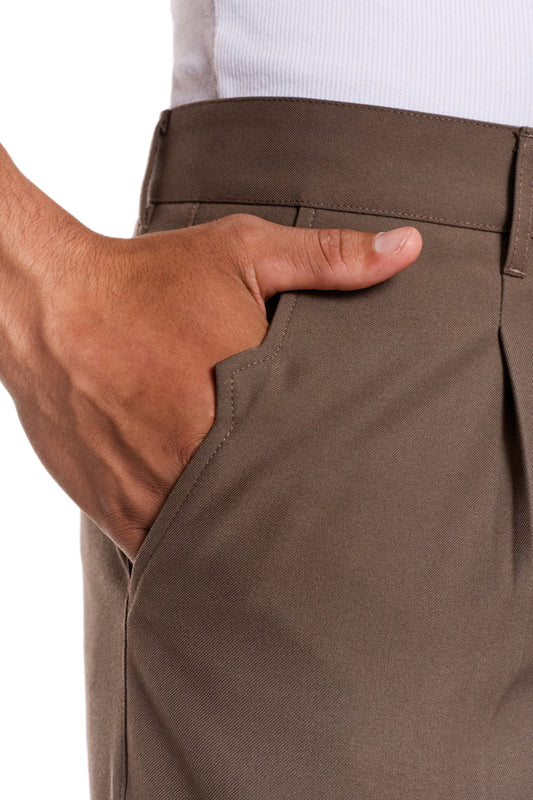 Hand in der Tasche der CC Dress Pants Slim Fit Braun, zeigt französische Taschen und Bundfalten, mit gesticktem OLAKALA-Logo über der rechten Gesäßtasche.