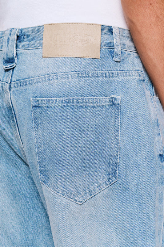 Rückansicht von CC Denim Pants Regular Blue mit Lederetikett und sichtbarem „Mittelfinger“ Patch an der Gürtelschlaufe.
