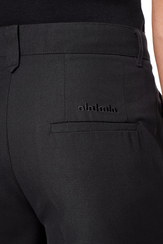 CC Dress Pants Slim Fit in Schwarz mit asymmetrischer Fronttasche, Bundfalten und gesticktem OLAKALA-Logo über der rechten Gesäßtasche.