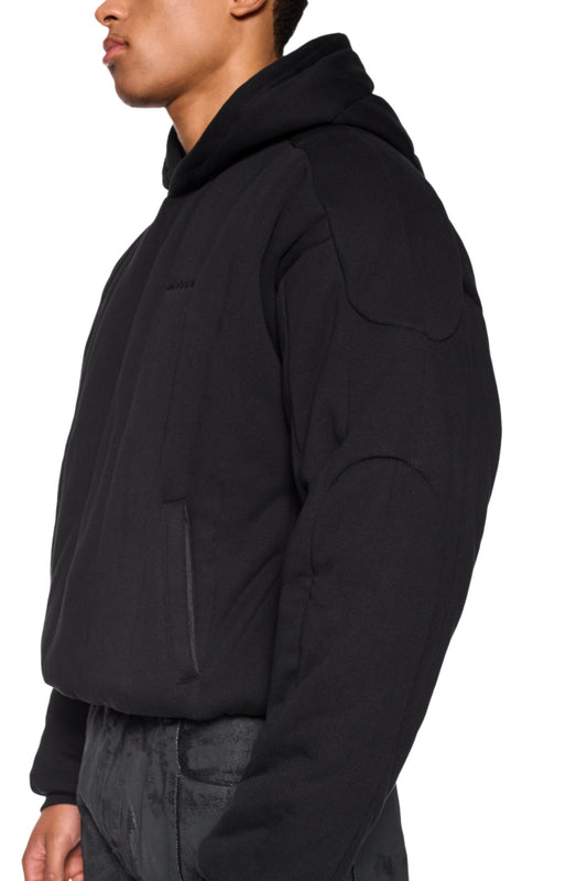 Person trägt den Greyzone Puffer Hoodie mit gesticktem OLAKALA Logo, oversized Passform und elastischem Saum, ideal für einen lässigen Look.