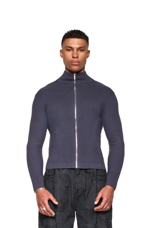 Mann trägt CI Slim Knit Jacket Gray mit Reißverschluss und schmaler Passform. Strickjacke zeigt verschiedene Strickmuster und betont die Hände.