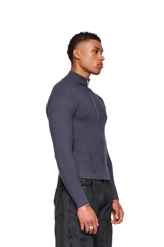 Mann trägt CI Slim Knit Jacket Gray mit verschiedenen Strickmustern und Reißverschluss. Schmale Passform, unisex, präsentiert von OLAKALA.