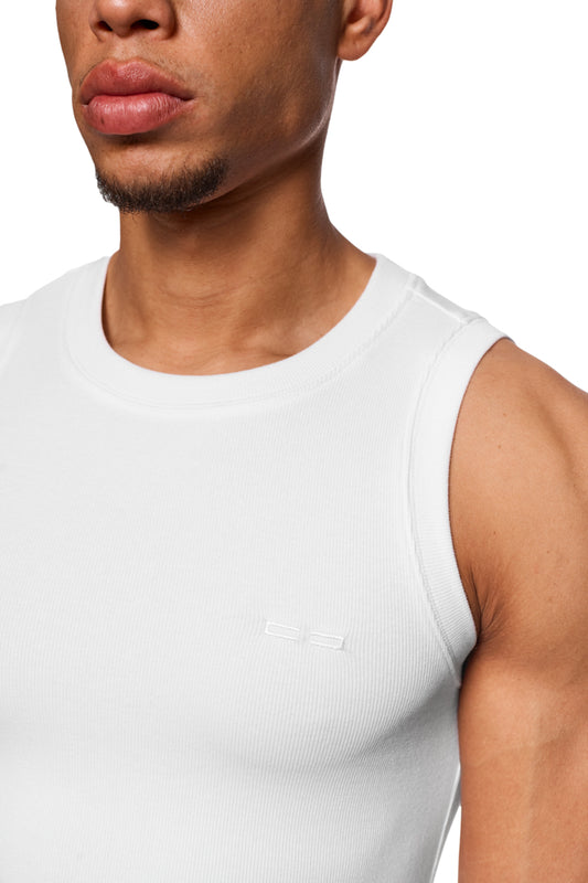 Nahaufnahme eines Mannes mit dem CC Core Tanktop Weiß aus elastischem Ripp-Stoff, zeigt das gestickte OLAKALA-Icon auf der linken Brust.